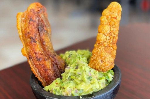 Guacamole con chicharrón at Goyo, served in a stone molcajete with two strips of chicharrón