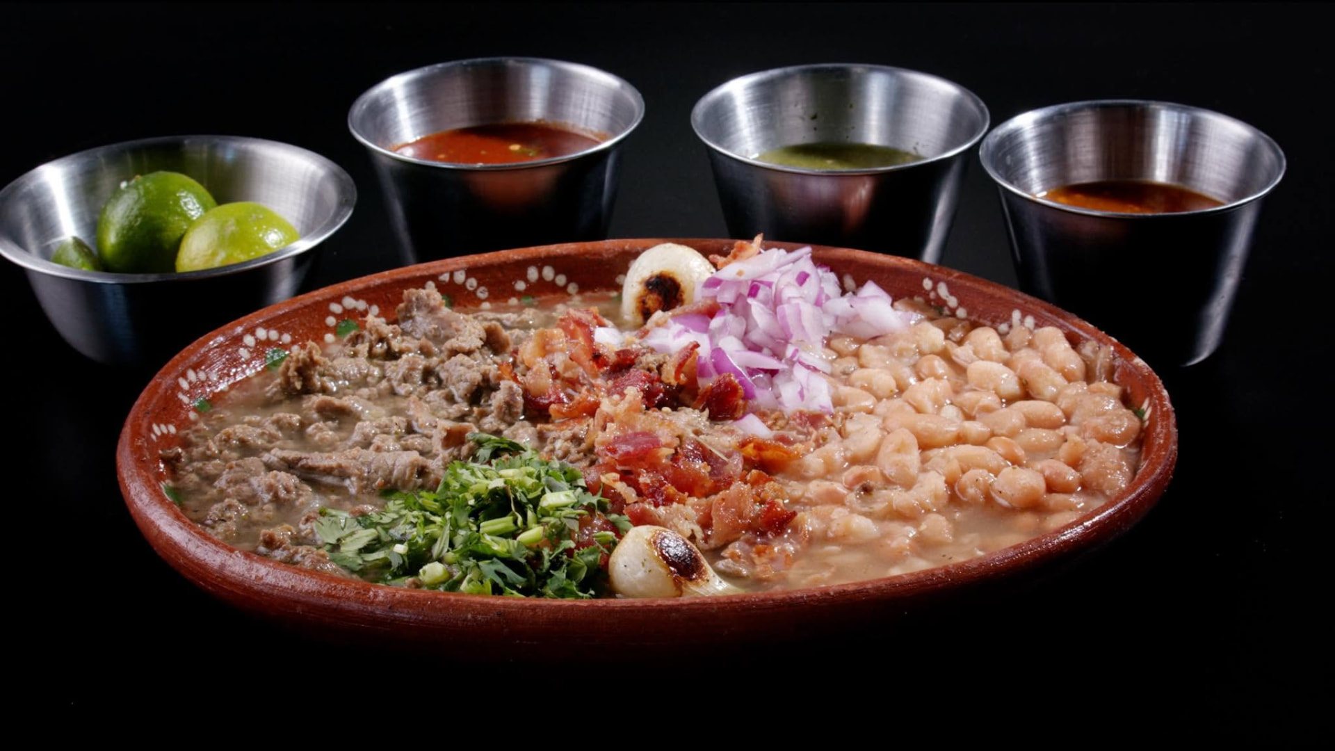 Carne en su jugo at Goyo with beans, bacon, red onion, cilantro, grilled onion, limes and four salsas